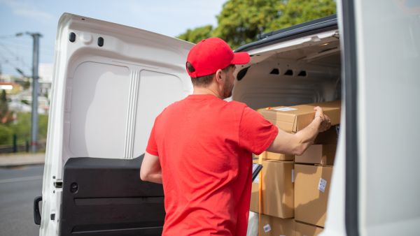 Entregador terminando de colocar itens para entrega no veículo de saída