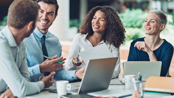 Equipe feliz discutindo assuntos de trabalho após a implementação de ações que promovem a saúde mental na empresa